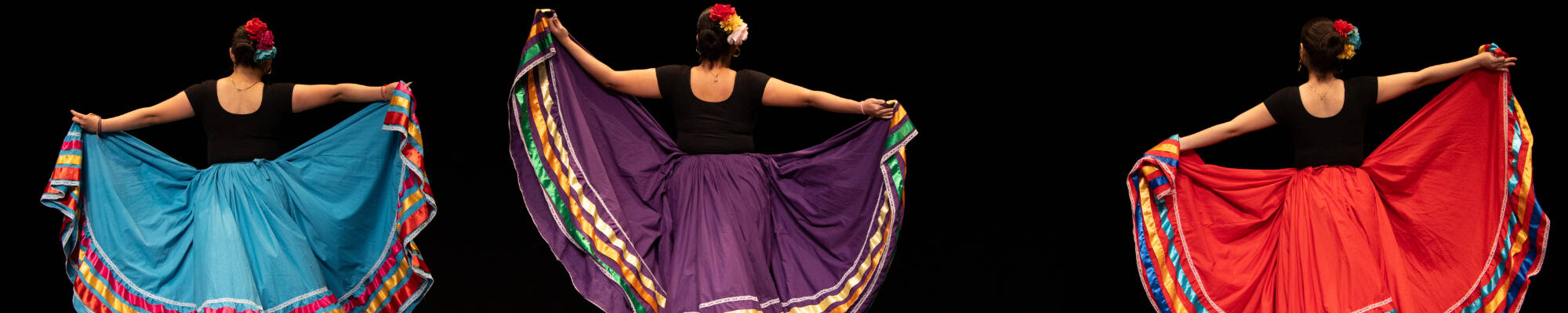Three people dancing with long, colorful skirts